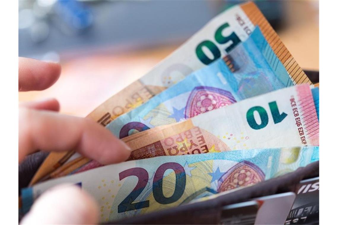 Bundesbank: Corona-Krise trifft Einkommen vieler Menschen Eine Frau hält eine Geldbörse mit Banknoten in der Hand. Foto: Monika Skolimowska/dpa-Zentralbild/dpa