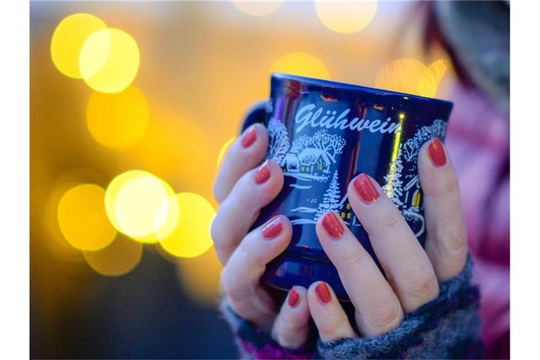 Eine Frau hält eine Tasse mit Glühwein in den Händen. Foto: Jens Kalaene/zb/dpa/Archivbild