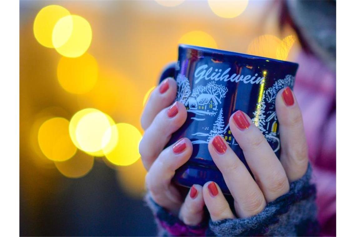 Corona macht Weihnachtsmärkten Strich durch die Rechnung Eine Frau hält eine Tasse mit Glühwein in den Händen. Foto: Jens Kalaene/zb/dpa/Archivbild