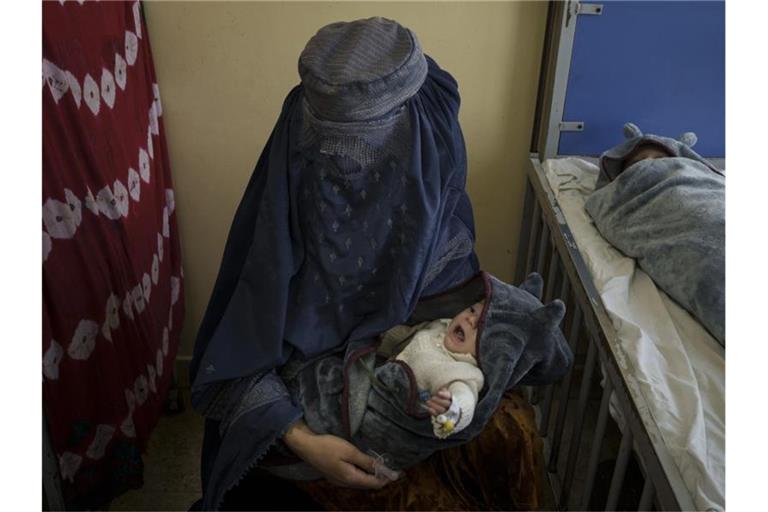 Eine Frau hält eines ihrer beiden Babys, die in Kabul behandelt werden, auf dem Arm. Foto: Felipe Dana/AP/dpa