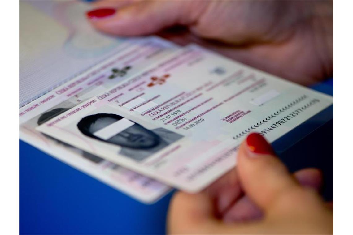 Eine Frau hält gefälschte Dokumente in den Händen. Foto: picture alliance / dpa / Symbolbild