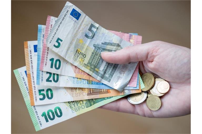 Eine Frau hält Geldscheine und Münzen in der Hand. Foto: Daniel Karmann/dpa/Symbolbild