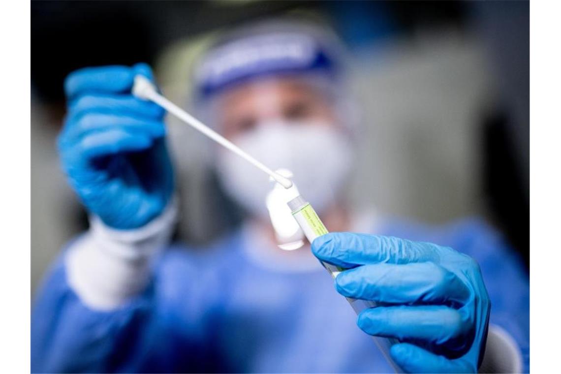 Eine Frau hält in einem Covid-19-Testcenter die Probe von einem Rachenabstrich in den Händen. Foto: Matthias Balk/dpa/Symbolbild