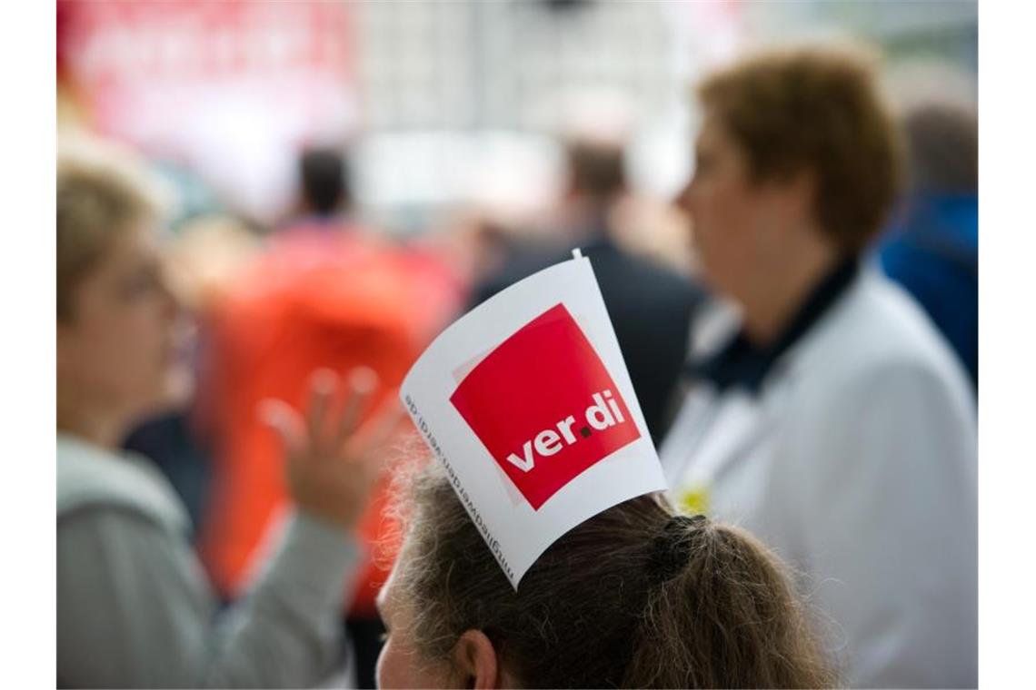 Trotz neuen Angebots keine Annäherung in Tarifrunde Eine Frau hat eine Verdi-Fahne in den Haaren stecken. Foto: Daniel Naupold/Archivbild
