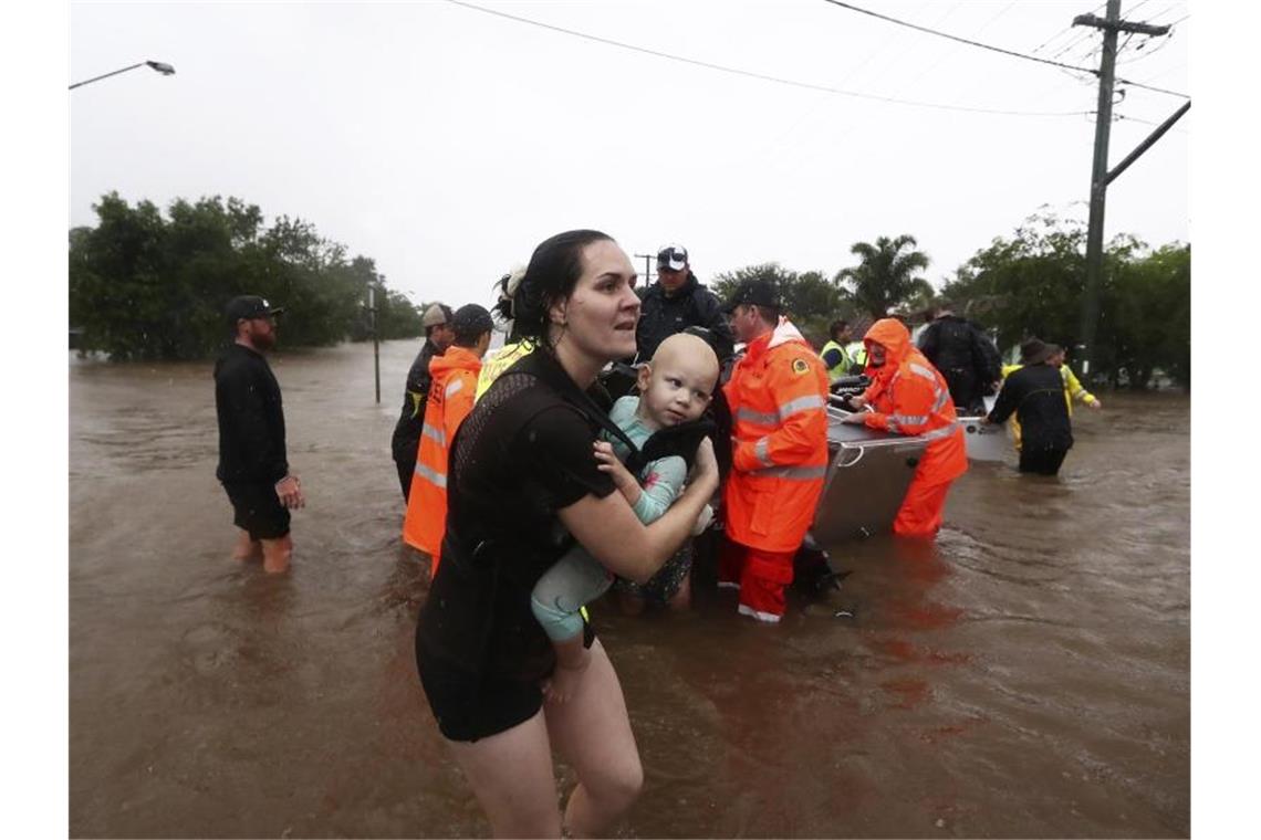 Historische Überschwemmungen in Australien Eine Frau im australischen Lismore sucht mit Baby Schutz vor den Fluten. Sintflutartiger Regen hat die schweren Überschwemmungen im Osten Australiens weiter verschärft. Foto: Jason O'brien/AAP/dpa