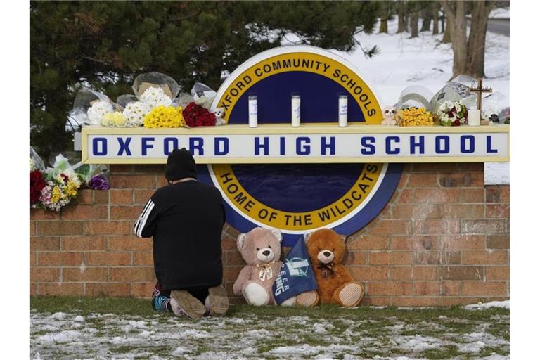 Eine Frau kniet zum Gebet vor dem Schild der Oxford High School im US-Bundesstaat Michigan. Ein 15-Jähriger hat dort mindestens vier seiner Mitschüler getötet. Foto: Paul Sancya/AP/dpa