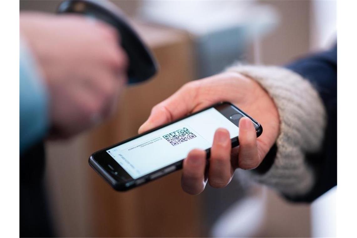 Eine Frau lässt am Eingang eines Corona-Schnelltest-Zentrums einen QR-Code auf ihrem Smartphone abscannen. Foto: Daniel Reinhardt/dpa