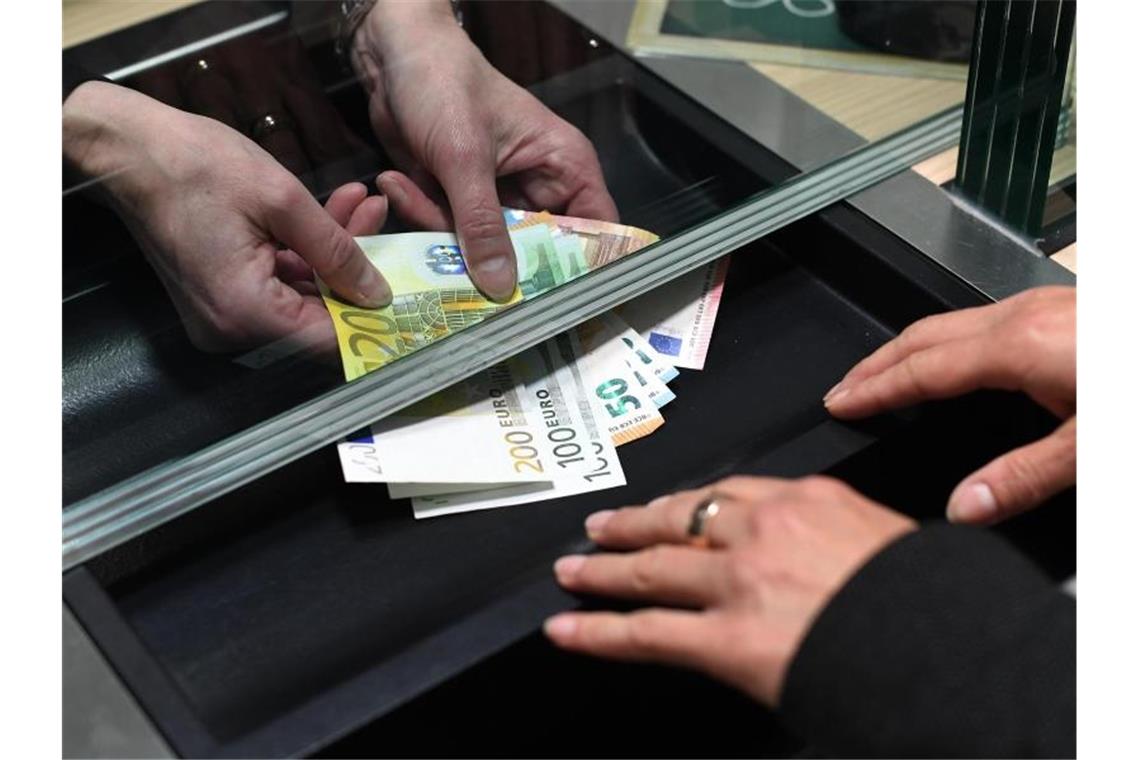Kunden gehen in Corona-Krise seltener zur Bankfiliale Eine Frau lässt sich in einer Bankfiliale am Schalter Bargeld auszahlen. Foto: Angelika Warmuth/dpa