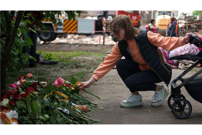 Eine Frau legt Blumen vor einem Haus ab, das nach einem russischen Angriff schwer beschädigt wurde. Nach Angaben von „Save the Children“ sind bislang mehr als 3.500 Kinder  in der Ukraine gestorben. (Archivfoto).