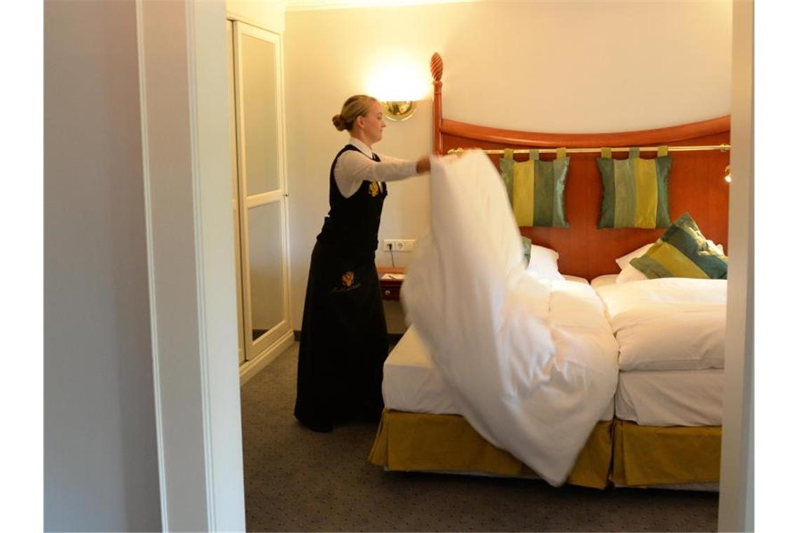 Eine Frau macht in einem Hotelzimmer das Bett. Foto: picture alliance/dpa/Archivbild