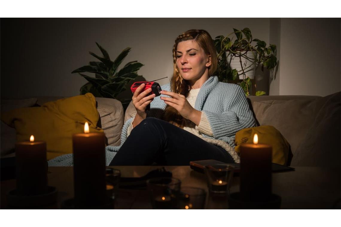 Eine Frau mit Kerzen während eines Stromausfalls. Ist der Strom länger weg, ist es meist weniger romantisch.