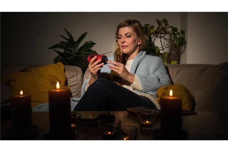 Eine Frau mit Kerzen während eines Stromausfalls. Ist der Strom länger weg, ist es meist weniger romantisch.
