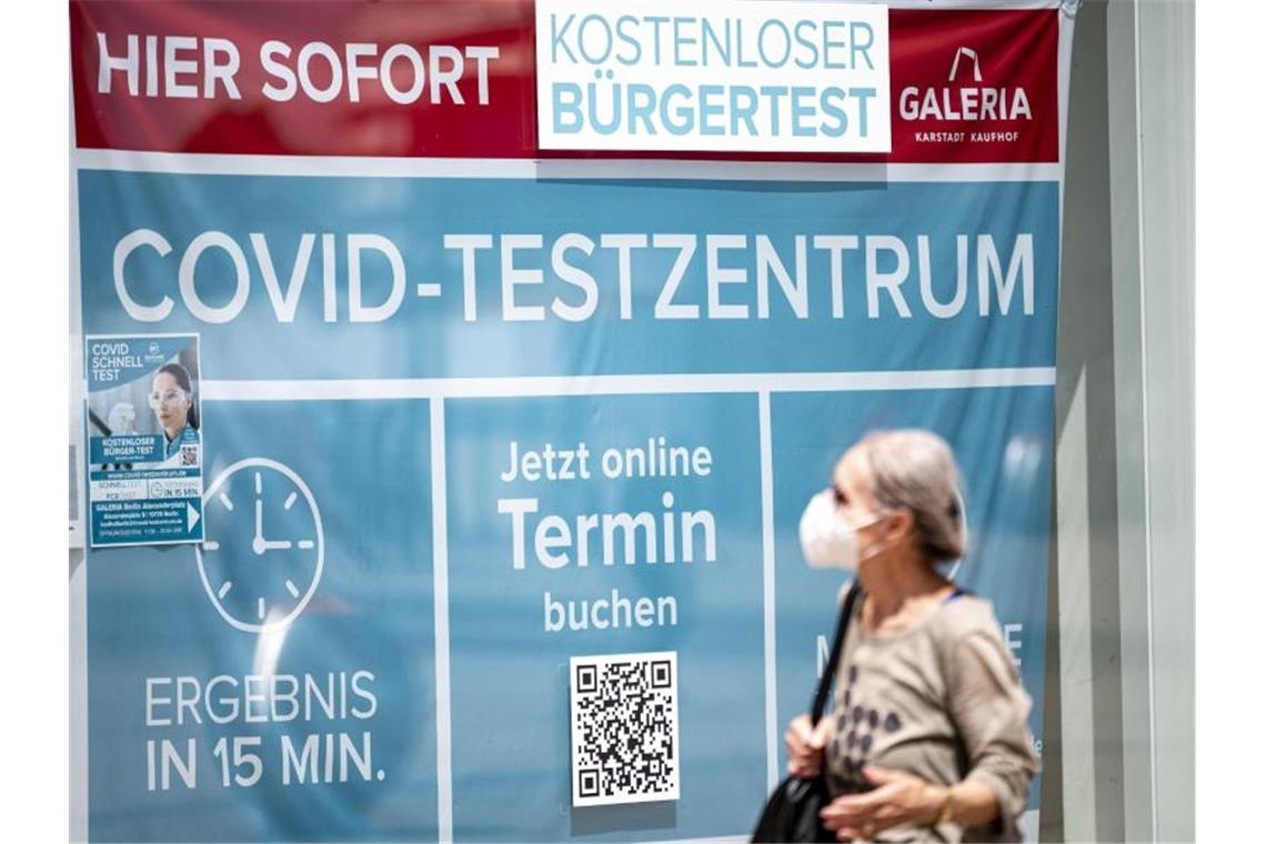 Eine Frau mit Maske läuft an einem Corona-Testzentrum am Berliner Alexanderplatz vorbei. Foto: Fabian Sommer/dpa