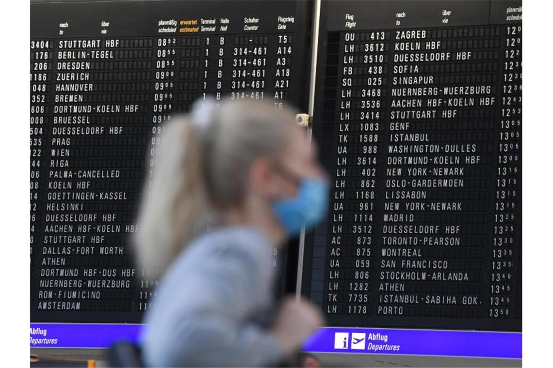 Deutsche Wirtschaft schlägt wegen Reisebeschränkungen Alarm Eine Frau mit Mundschutz im Terminal 1 des Frankfurter Flughafens. Foto: Arne Dedert/dpa