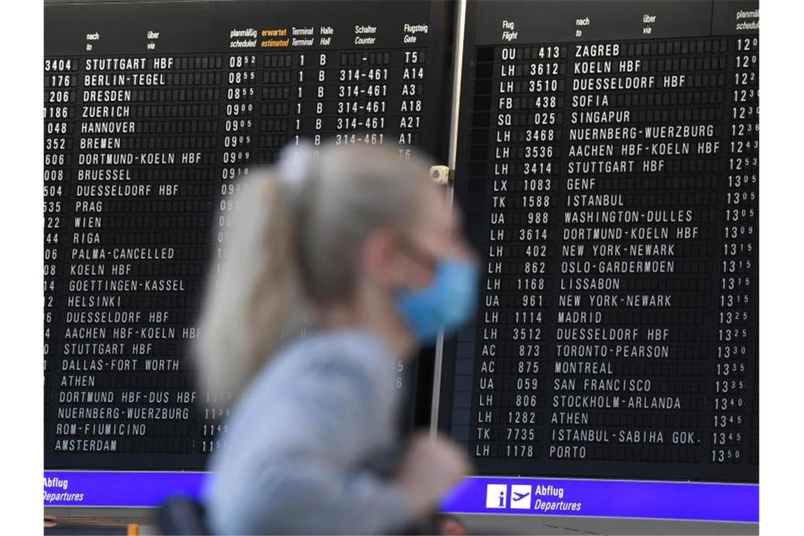 Eine Frau mit Mundschutz im Terminal 1 des Frankfurter Flughafens. Foto: Arne Dedert/dpa