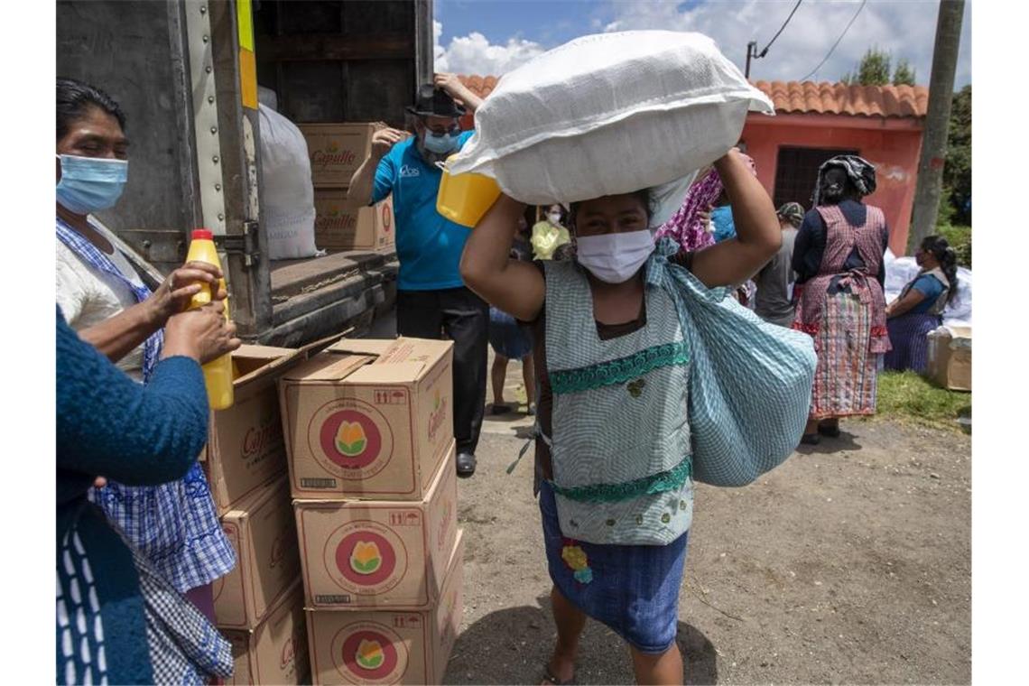 Oxfam: Pandemie droht soziale Ungleichheit zu verschärfen Eine Frau mit Mundschutz macht sich in San Jose Calderas, Guatemala, mit einem Sack voll Hilfsgütern auf den Heimweg. Foto: Moises Castillo/AP/dpa