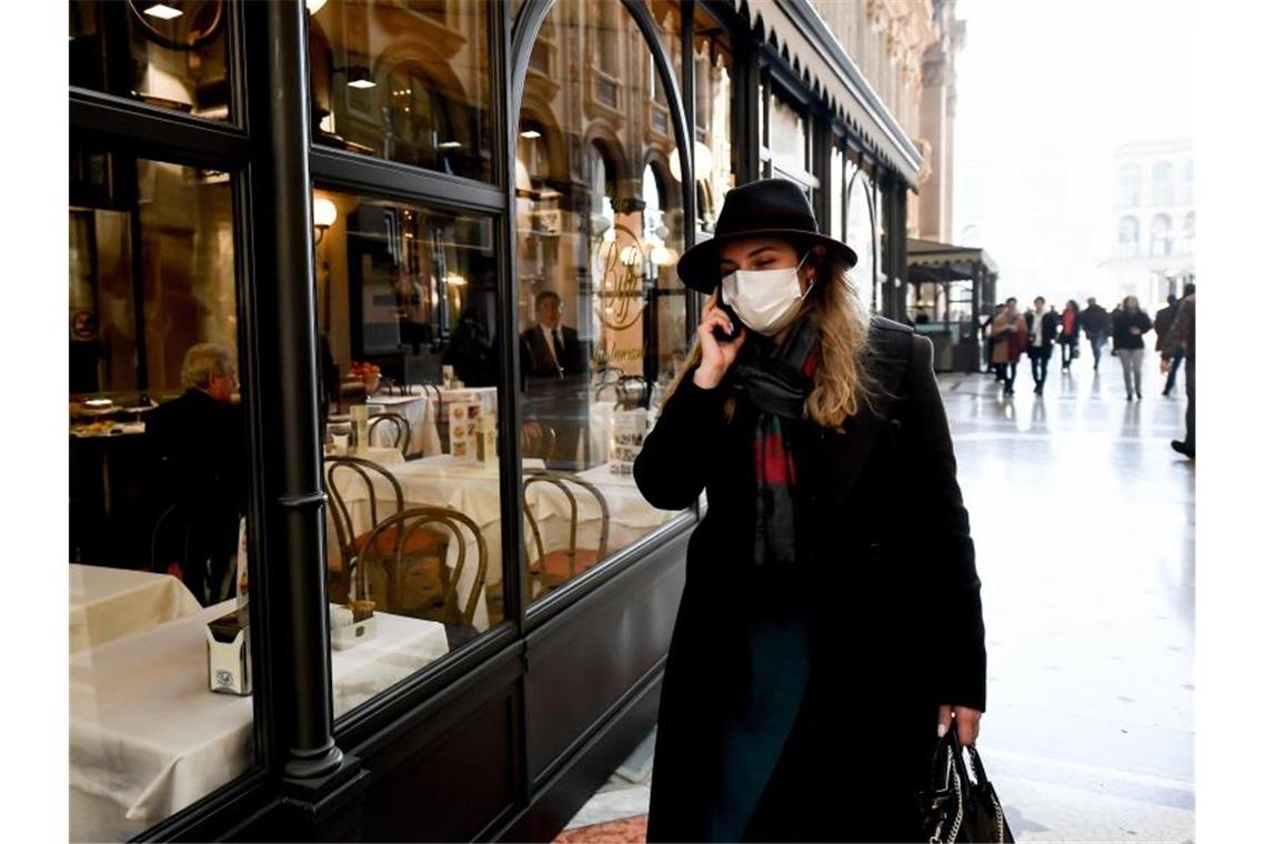 Eine Frau mit Mundschutz vor einem Restaurant in Mailand. Foto: Claudio Furlan/LaPresse via ZUMA Press/dpa