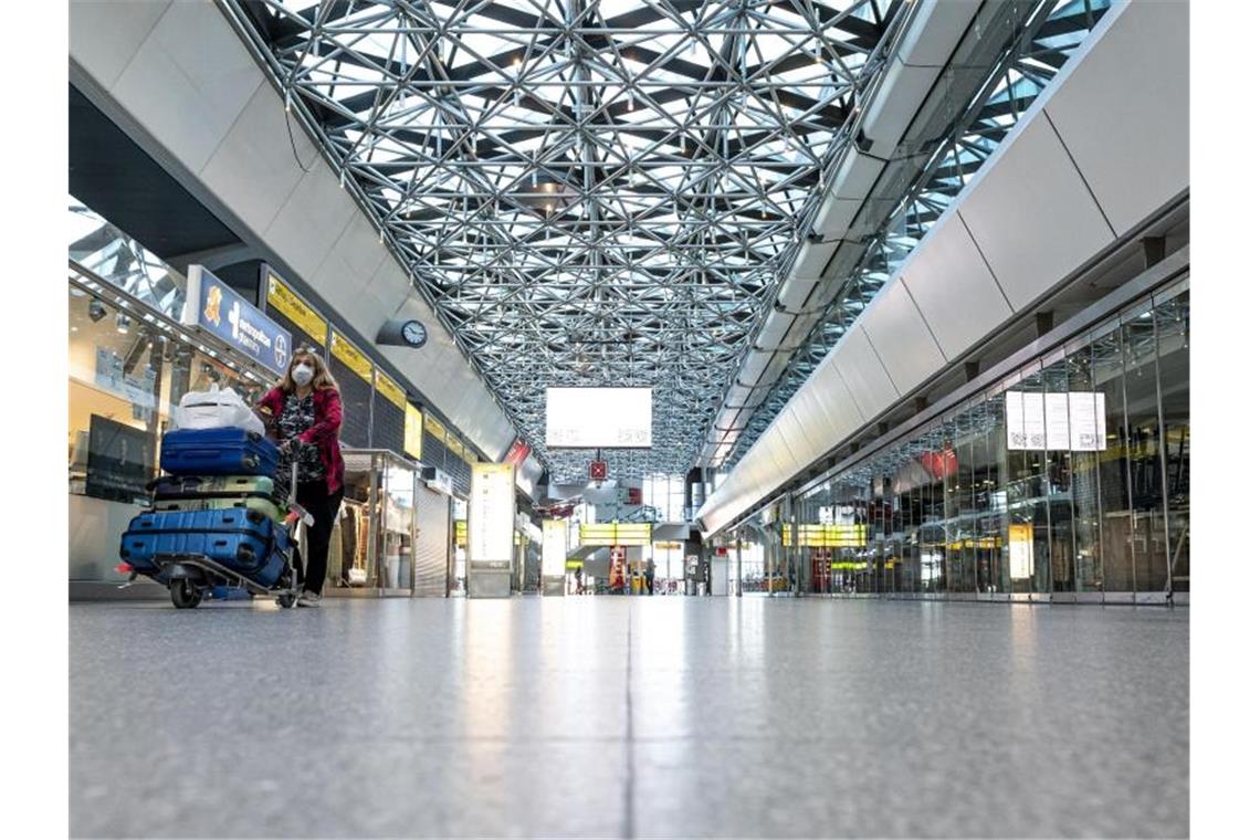 Eine Frau mit Mundschutzmaske läuft durch die ansonsten leere Haupthalle des Flughafens Tegel. Foto: Fabian Sommer/dpa