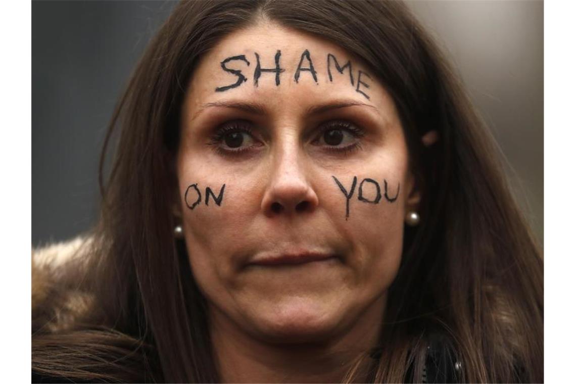 Eine Frau nimmt an einer Demonstration vor dem New Scotland Yard in London teil und trägt den Schriftzug „Shame On You“ auf ihrem Gesicht. Foto: Frank Augstein/AP/dpa