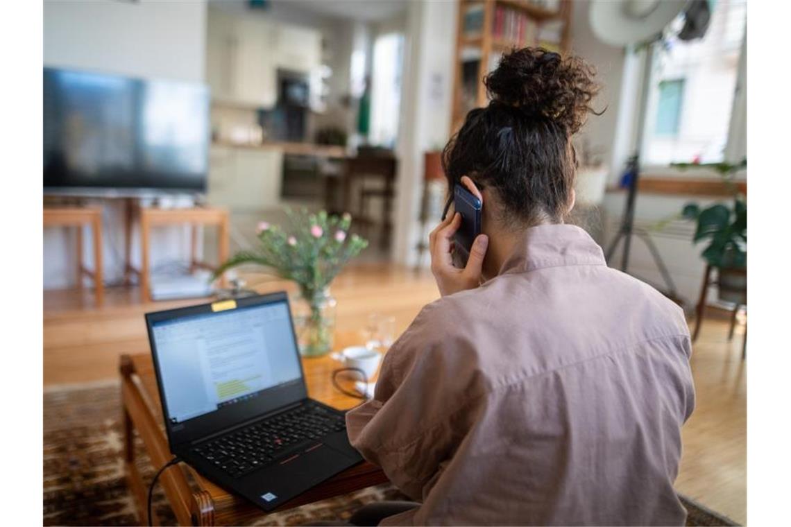 Eine Frau nimmt im Homeoffice aus ihrem Wohnzimmer an einer Telefonkonferenz teil. Foto: Sebastian Gollnow/dpa