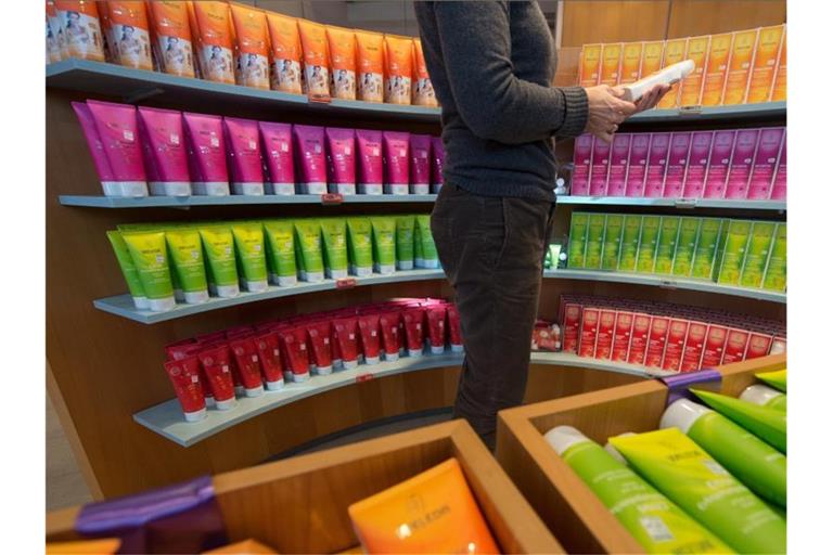 Eine Frau nimmt in einer Apotheke ein Produkt des Naturkosmetikherstellers Weleda aus einem Regal. Foto: Marijan Murat/Archivbild