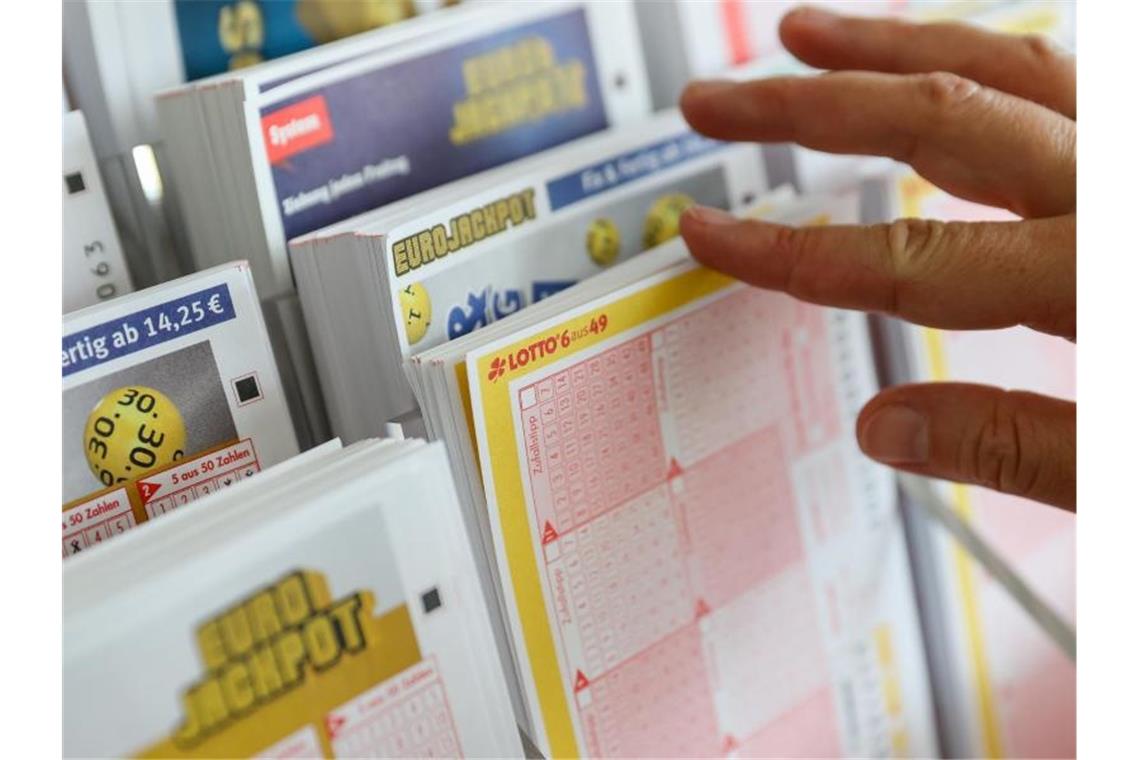 Eine Frau nimmt sich einen Lottoschein. Foto: Jan Woitas/dpa-Zentralbild/dpa/Illustration