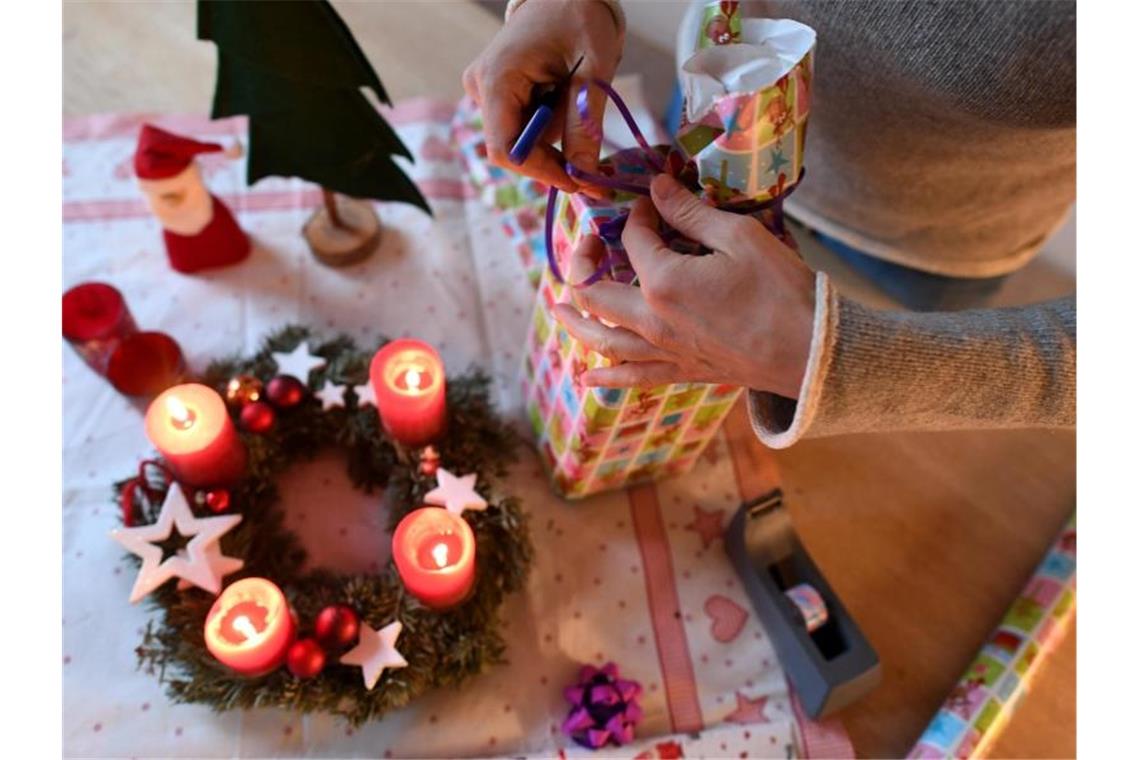 Eine Frau packt am vierten Advent Weihnachtsgeschenke ein. Foto: Angelika Warmuth/dpa
