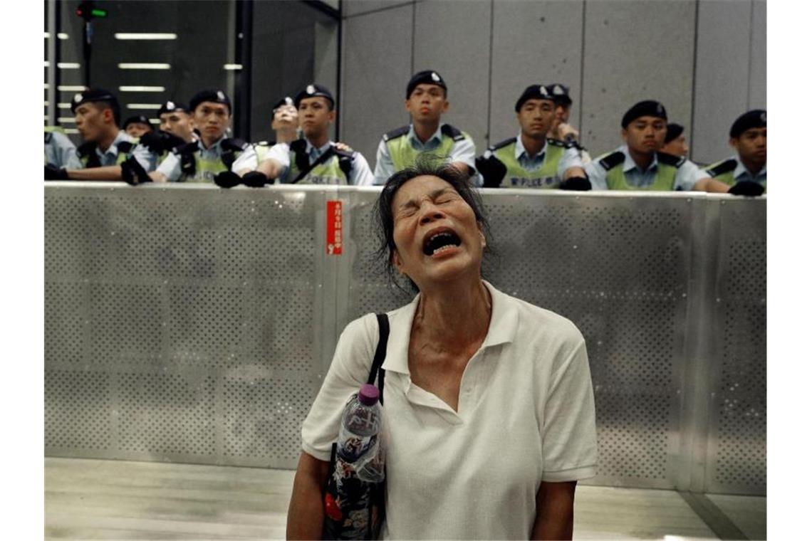 Eine Frau reagiert während Demonstranten und Polizisten während eines Protests gegen das von der Regierung geplante Auslieferungsgesetz zusammenstoßen. Foto: Vincent Yu/AP