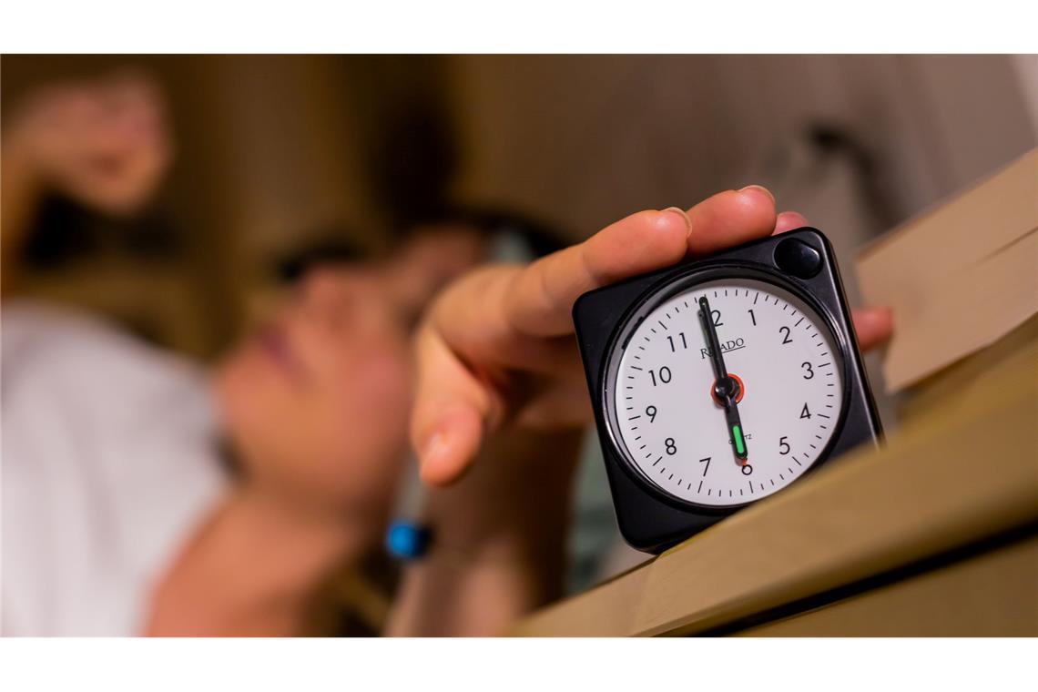 Nur noch fünf Minuten: Schlummertaste in Deutschland beliebt Eine Frau schaltet vom Bett aus einen auf sechs Uhr gestellten Wecker aus.