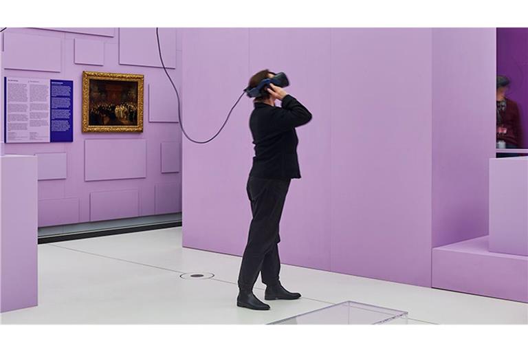 Eine Frau schaut sich die Ausstellung „Kunst als Beute“ mit VR-Brille im Humboldt-Forum an.