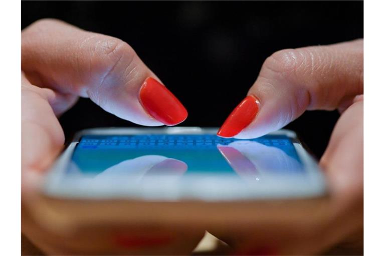 Eine Frau schreibt eine Nachricht auf ihrem Smartphone. (Archivbild). Foto: Patrick Pleul/dpa-Zentralbild/dpa