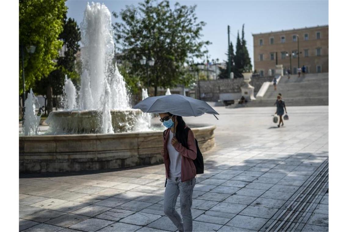 Zweitwärmster jemals gemessener Juli in Europa Eine Frau schützt sich bei Temperaturen über 40 Grad in Athen mit einem Schirm vor Sonne und Hitze. Foto: Angelos Tzortzinis/dpa