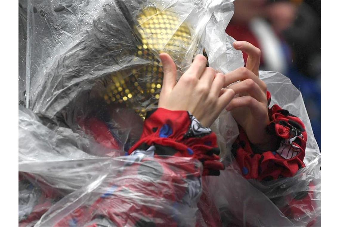 Eine Frau schützt sich mit einem Poncho vor dem Regen beim Rosenmontagszug in Köln (Archiv). Auch in diesem Jahr soll es in den Karnevalshochburgen nass werden. Foto: Federico Gambarini/dpa