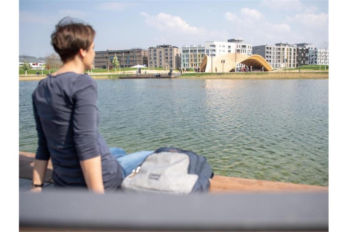 Eine Frau sitzt auf dem Gelände der Bundesgartenschau (Buga) Heilbronn 2019 an einem See. Foto: Sebastian Gollnow/dpa