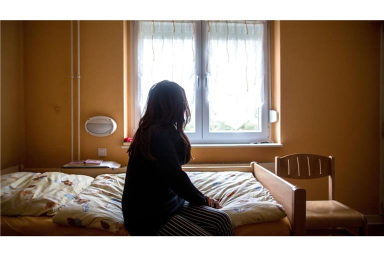 Eine Frau sitzt in einem Frauenhaus auf einem Bett. In Deutschland fehlen über 13.000 Frauenhausplätze (Symbolfoto).