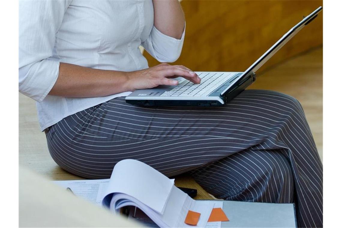 Mehr Frauen promovieren im Südwesten Eine Frau sitzt mit Aktenordner und Laptop auf einer Bank. Foto: Patrick Pleul/zb/dpa/Illustration