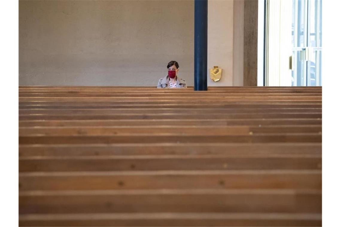 Eine Frau sitzt mit Mundschutz in der ansonsten fast menschenleeren St. Matthäuskirche in München. Ab 4. Mai sind Gottesdienste auch in Bayern wieder erlaubt. Foto: Sven Hoppe/dpa