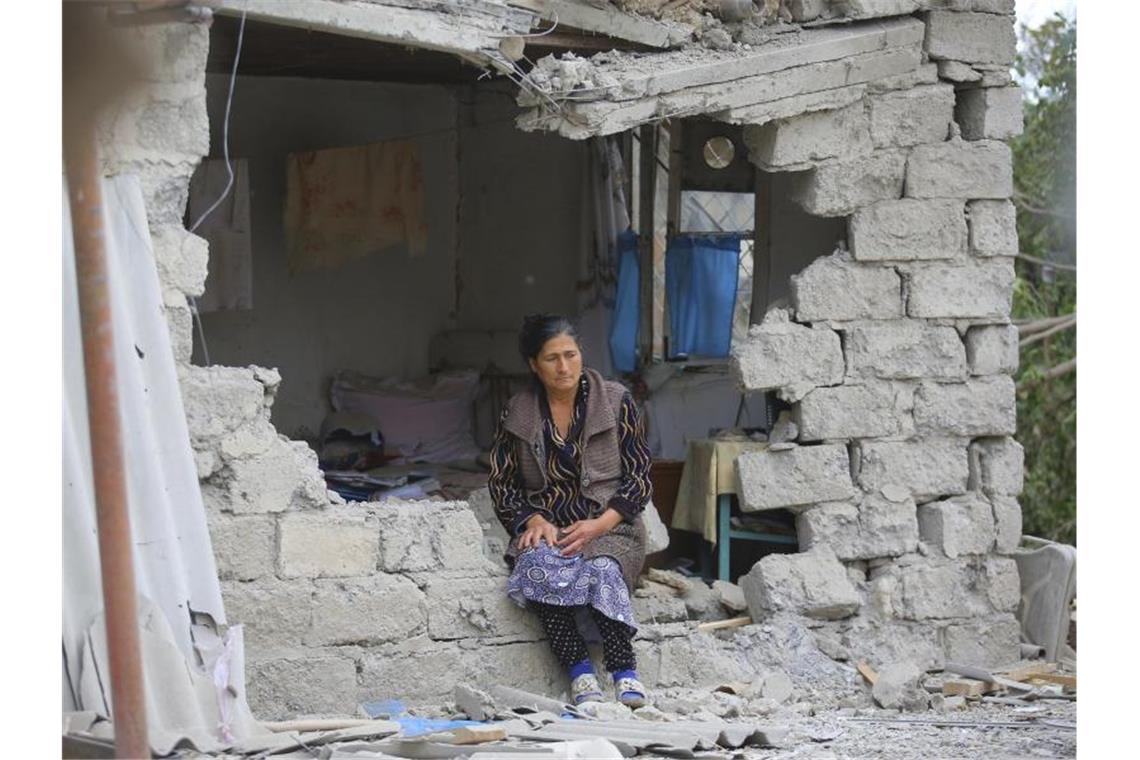Eine Frau sitzt nach einem Beschuss der armenischen Artillerie inmitten der Trümmer ihres Hauses. Foto: Aziz Karimov/AP/dpa
