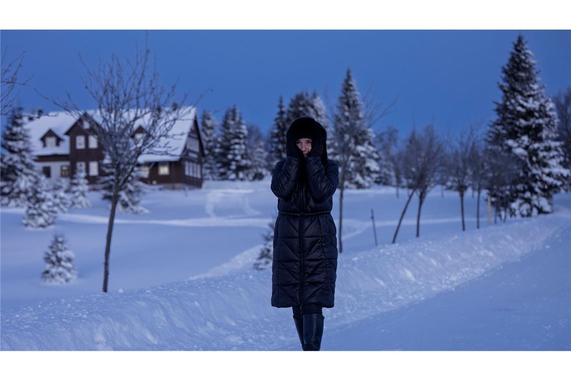 Eine Frau spaziert durch eine verschneite Landschaft in Tschechien.