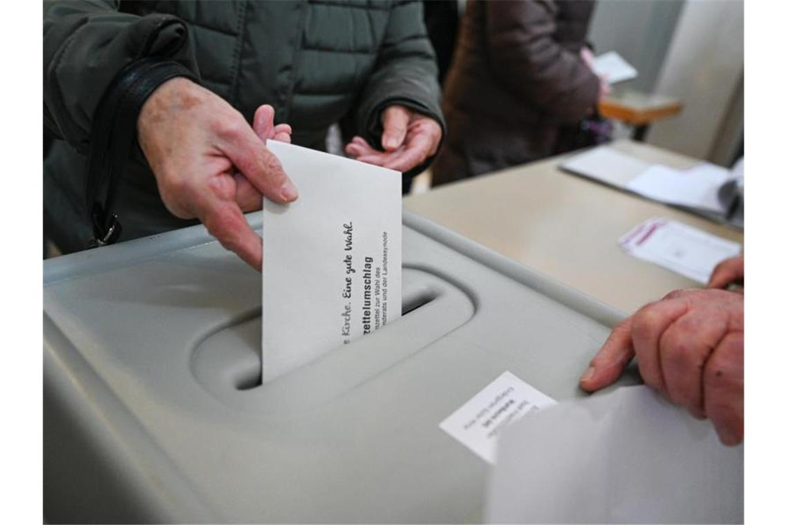 Eine Frau steckt bei der Wahl der Evangelischen Landeskirche ihren Stimmzettel in die Wahlurne. Foto: Felix Kästle/dpa