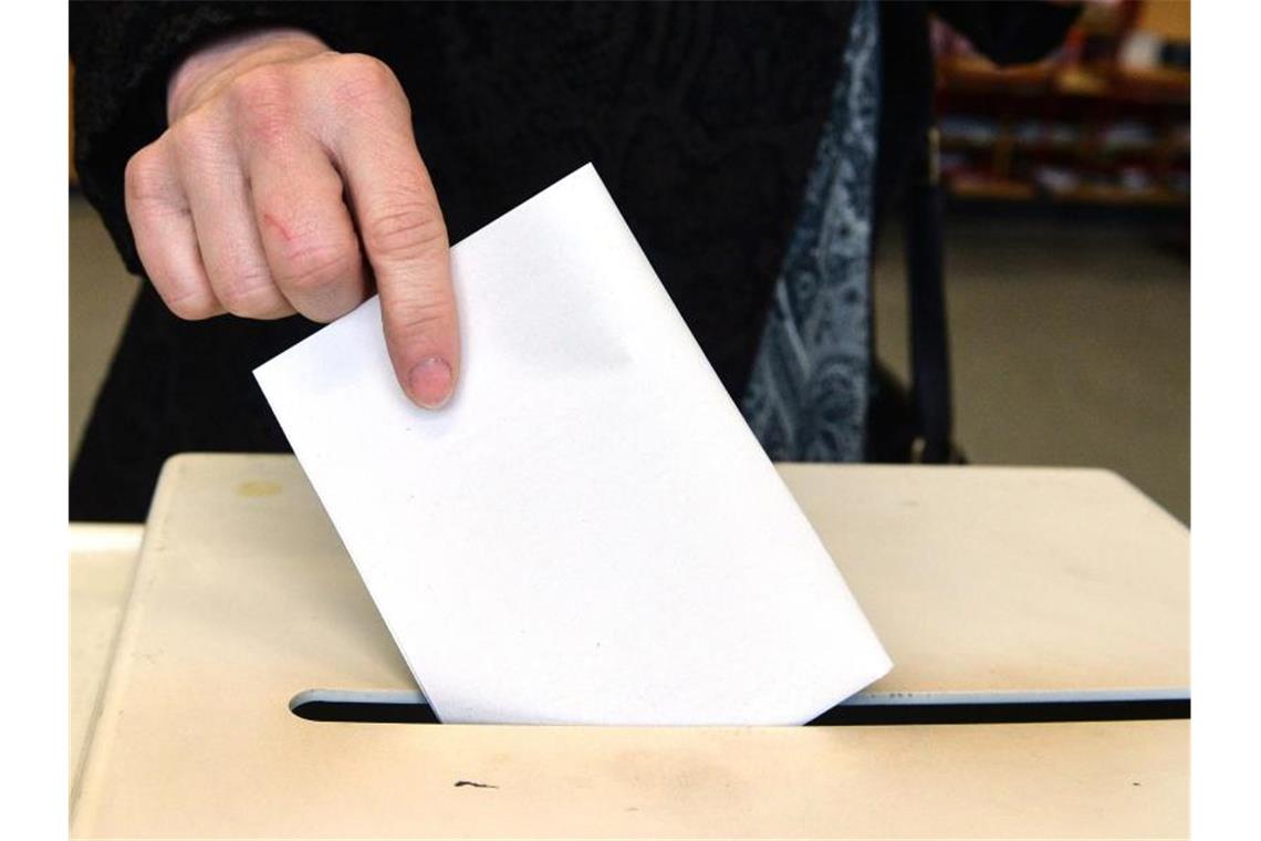 Eine Frau steckt in einem Wahllokal ihren Stimmzettel für die Landtagswahl in Baden-Württemberg in eine Wahlurne. Foto: Thomas Kienzle/dpa/Archivbild