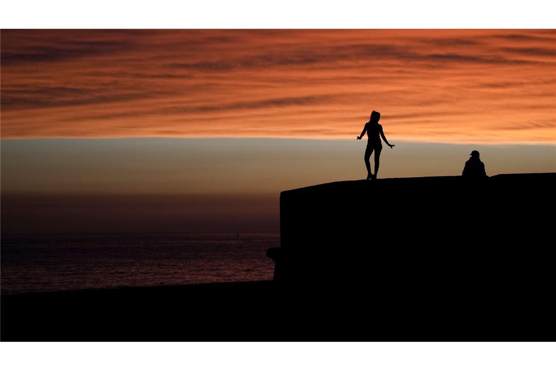 Bilder des Tages Eine Frau steht an der Uferpromenade von Montevideo in Uruguay vor dem Hintergrund des Sonnenuntergangs.
