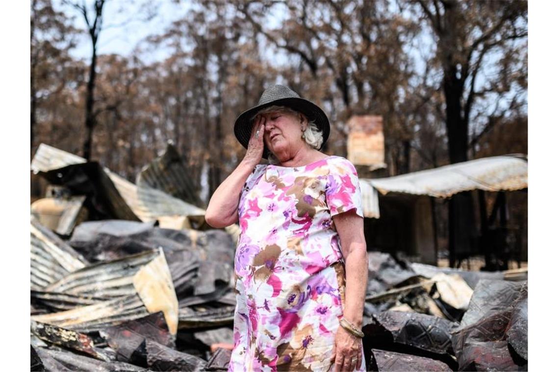 Eine Frau steht im Ort Mogo vor den Überresten ihres Geschäfts, das an Silvester abgebrannt ist. Foto: James Gourley/AAP/dpa