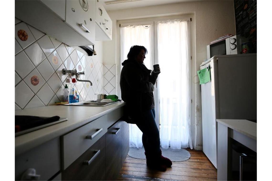 Eine Frau steht in ihrer Küche. Foto: Roland Weihrauch/dpa/Illustration