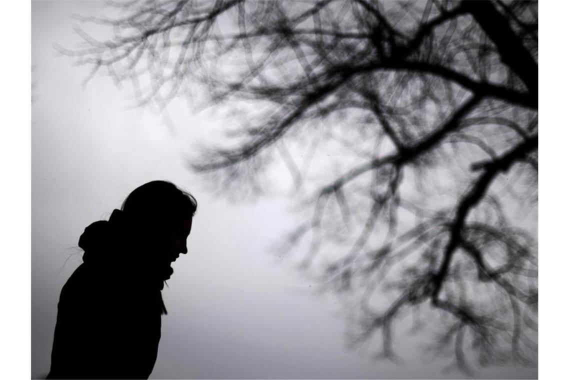 Psychische Erkrankungen: ZI treibt Erste Hilfe voran Eine Frau steht neben einem Baum. Foto: Julian Stratenschulte/dpa/Illustration