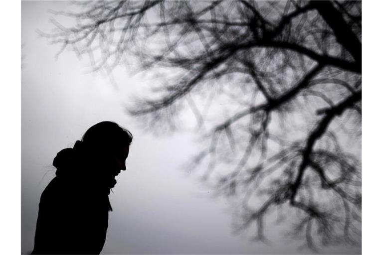 Eine Frau steht neben einem Baum. Foto: Julian Stratenschulte/dpa/Illustration