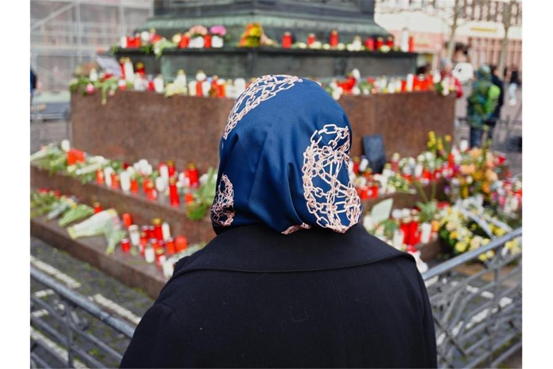 Eine Frau steht vor dem Hanauer Brüder Grimm Denkmal, an dem Blumen und Kerzen niedergelegt worden sind. Foto: Nicolas Armer/dpa