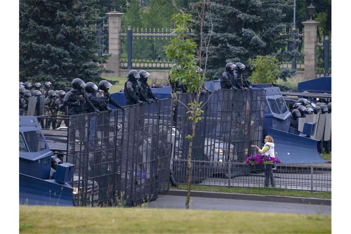 Eine Frau steht vor einer Barrikade von Bereitschaftspolizisten. Foto: Sergei Grits/AP/dpa