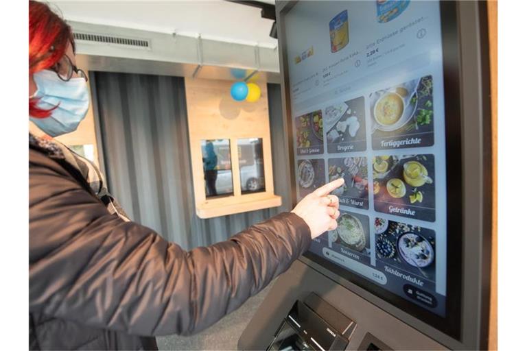 Eine Frau steht zur Vorstellung eines voll automatisierten Edeka-Supermarktes an einem Automaten. Foto: Sebastian Gollnow/dpa