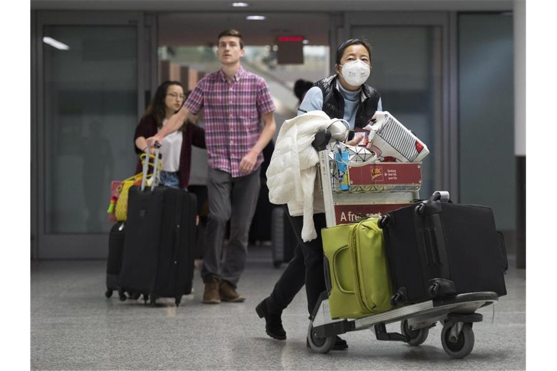 Eine Frau trägt am Toronto Pearson International Airport eine Atemschutz-Maske. Immer mehr Länder prüfen eine Evakuierung ihrer Landsleute. Foto: Nathan Denette/The Canadian Press/AP/dpa